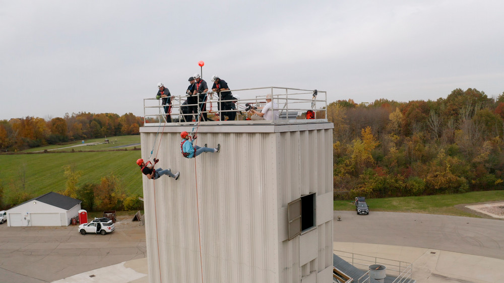 Macomb County Executive Mark Hackel and State Representative Denise Mentzer rappel down the five-story burn tower at Macomb Community College's Public Service Institute